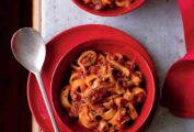 A red bowl with Christmas Eve calamari--calamari, onion, garlic, red pepper flakes in a tomato sauce.