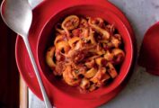 A red bowl with Christmas Eve calamari--calamari, onion, garlic, red pepper flakes in a tomato sauce.
