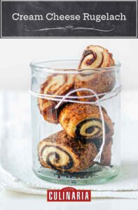Four cream cheese rugelach in a glass jar with twine wrapped around it.