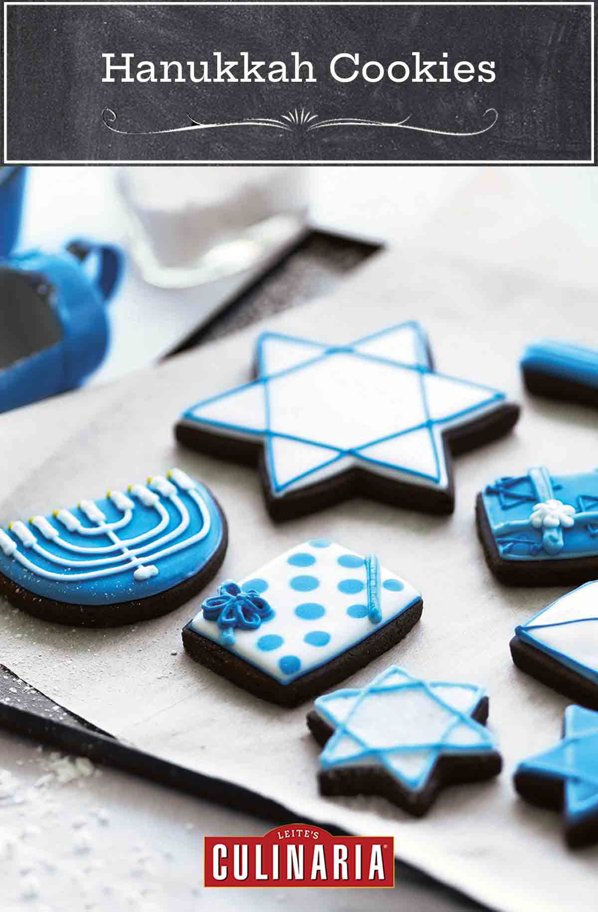 A selection of frosted cookies decorated for Hanukkah, on a parchment-lined cookie sheet.
