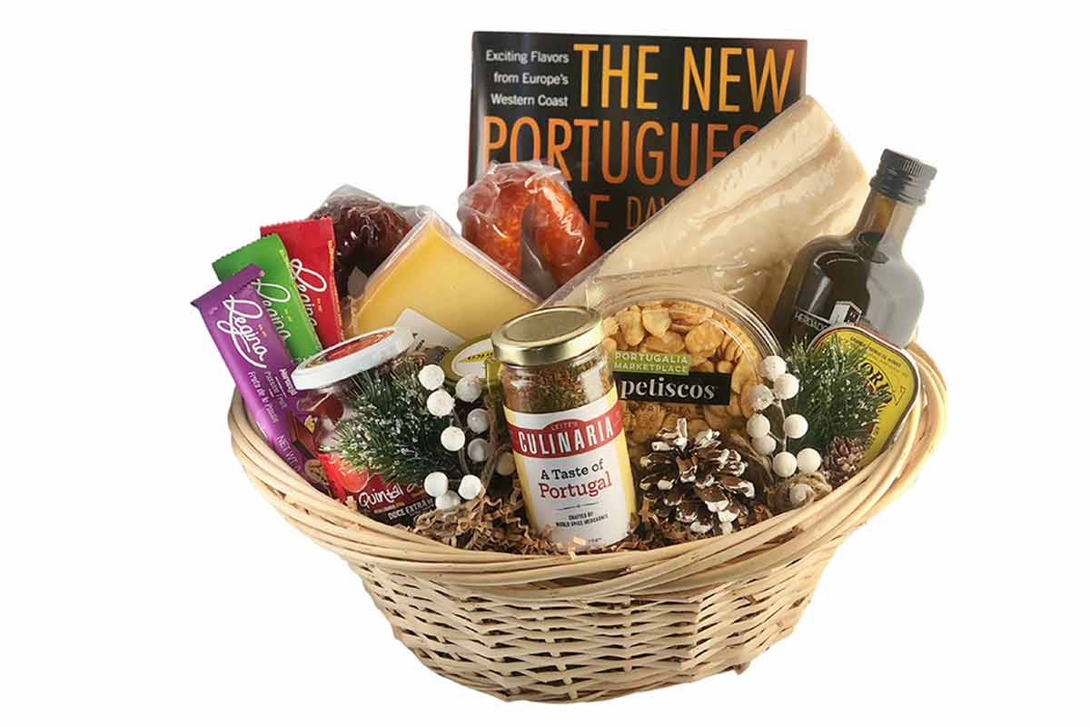 A wicker basket with spices, cheese, olive oil, chocolates, and a cookbook.