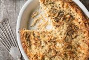 Oval dish with noodle kugel, a cheese and pepper casserole with fettuccine and ricotta and Pecorino cheeses baked golden.