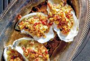 A tray of oysters Rockefeller with bacon--baked oysters topped with bread crumbs, bacon, and butter.