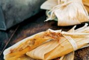 Two wrapped tamales on top of an open corn husk.