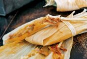 Two wrapped tamales on top of an open corn husk.