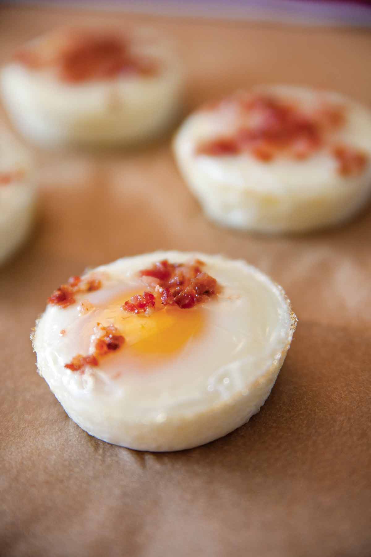 Four baked eggs sprinkled with chopped bacon.