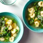 Two bowls filled with tortellini, peas, and spinach.