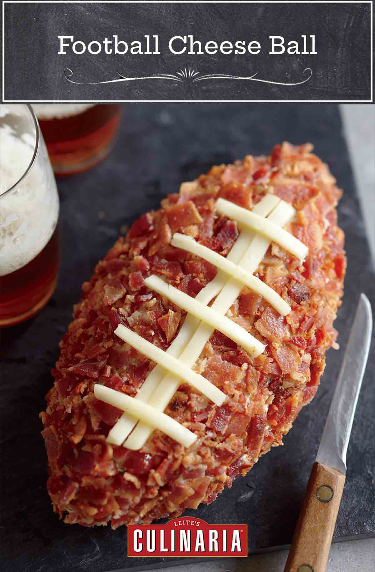 A football cheese ball on a serving board with two glasses of beer and a knife beside it.