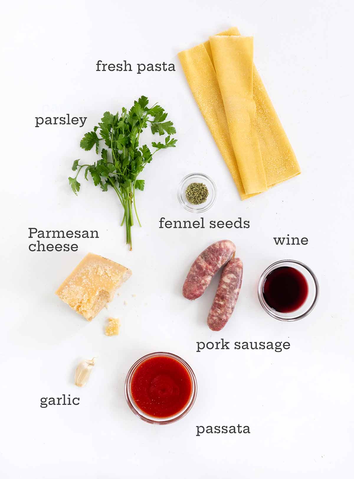 Ingredients for sausage pappardelle--parsley, fresh pasta, Parmesan, fennel, sausage, wine, and passata.