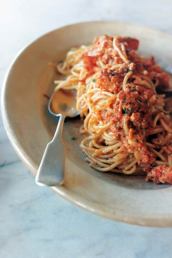 An oval plate topped with lobster fra diavolo and a spoon resting on the side.