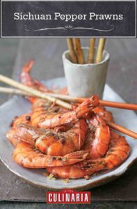 An oval ceramic platter topped with Sichuan pepper prawns and bamboo sticks crossed over the top of them.