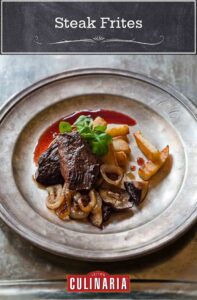 Pieces of steak frites on a metal plate with a side of sautéed onions and mushrooms and garnished with parsley.