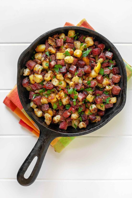 A small skillet full with corned beef hash on a dish towel.