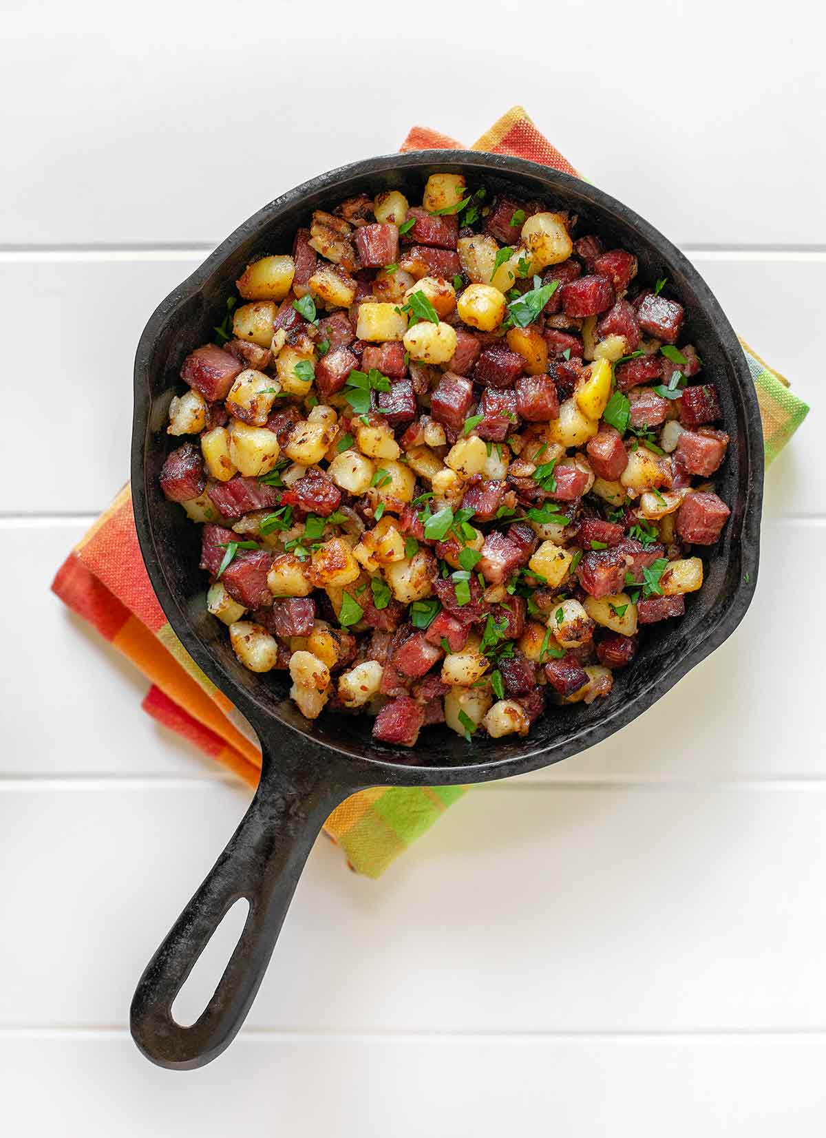 A small pan full of corned beef hash on a tea towel.