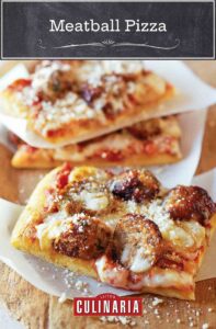 Three square slices of meatball pizza on strips of parchment paper, with fresh Parmesan sprinkled overtop.