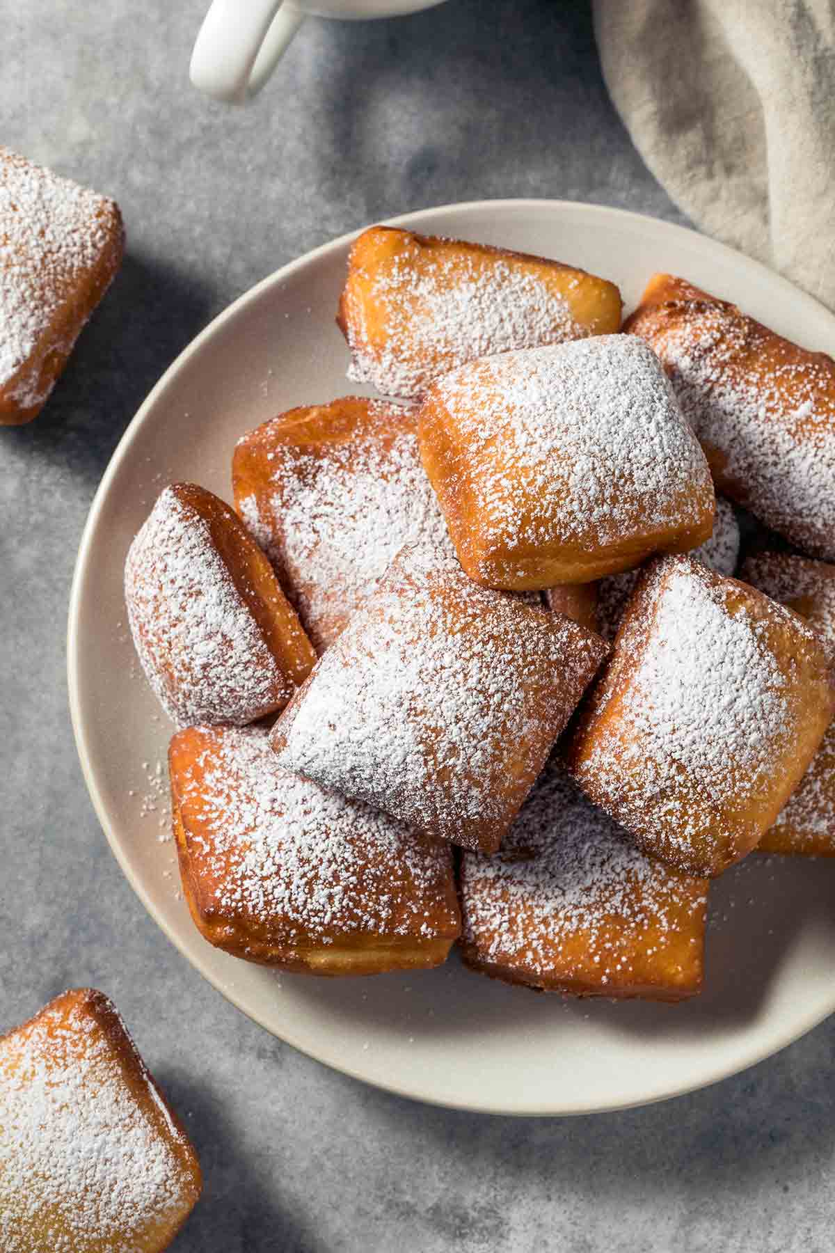 A pile of beignets dusted with confectioners' sugar in a bowl.