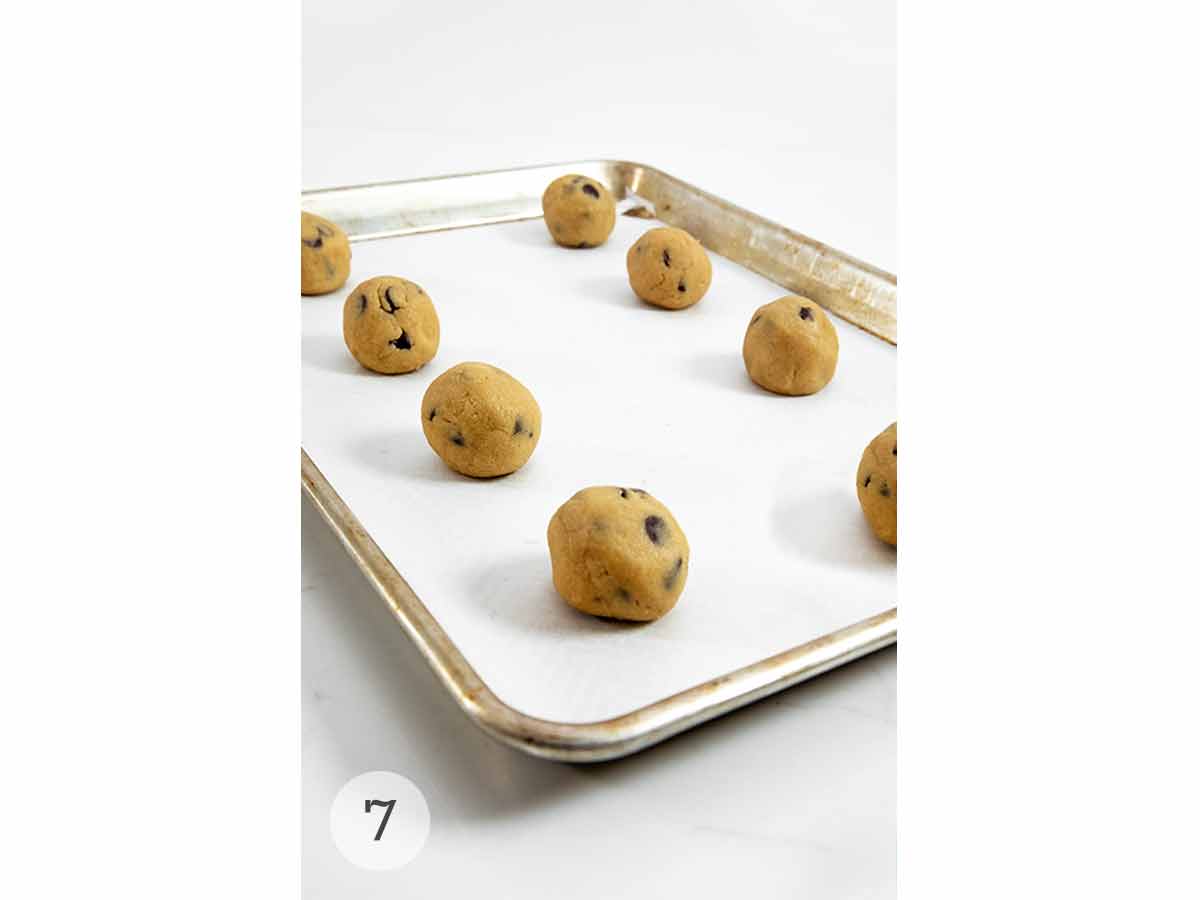 A baking sheet with unbaked chocolate chip cookie dough on it.