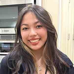 An Asian woman with long hair smiling.