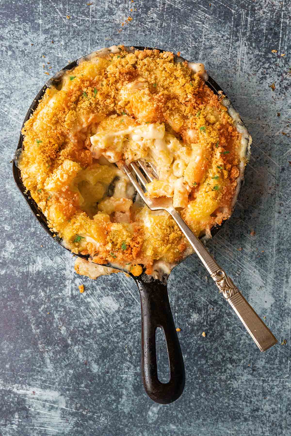 A small cast-iron skillet filled with Brie mac and cheese with a fork digging into it.