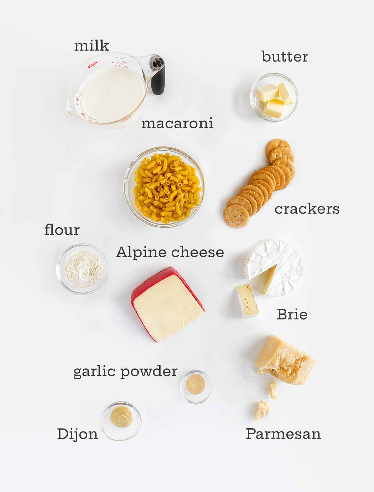 Ingredients for Brie mac and cheese -- Brie, pasta, crackers, butter, milk, flour, cheese, butter, garlic powder, and Dijon.