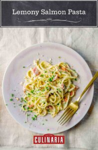 A white plate topped with a pile of lemony salmon pasta, sprinkled with chives.