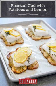 A parchment-lined baking sheet with four roasted cod fillet on top of roasted potatoes slices and topped with lemon slices.