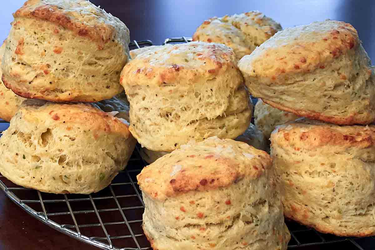 Several Parmesan cheese biscuits stacked on a wire cooling rack.