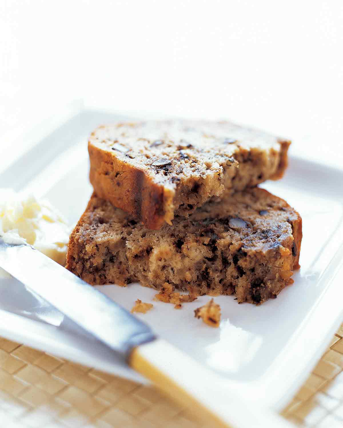 A broken slice of banana bread stacked on a white plate