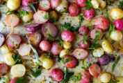 Oven roasted radishes topped with herbs on a baking sheet.