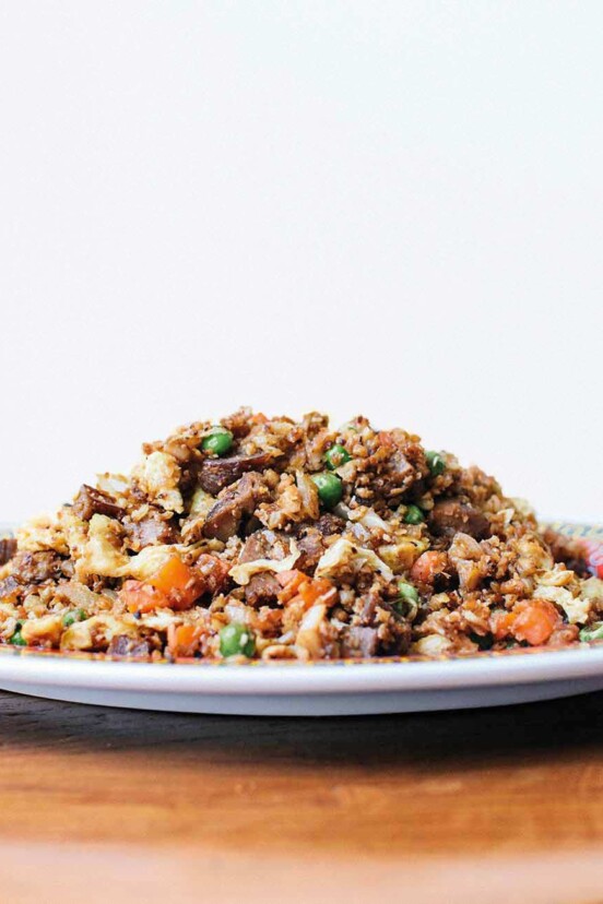 A plate mounded with cauliflower fried rice on a wooden table.