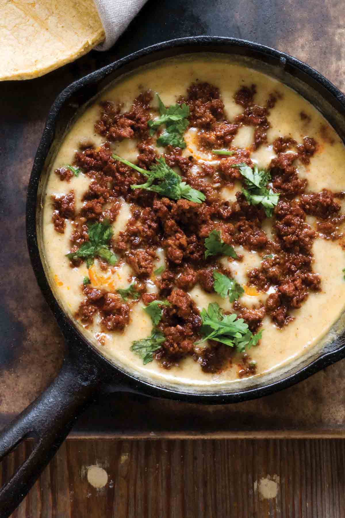 A cast-iron skilled filled with choriqueso, a cheese dip topped with queso.
