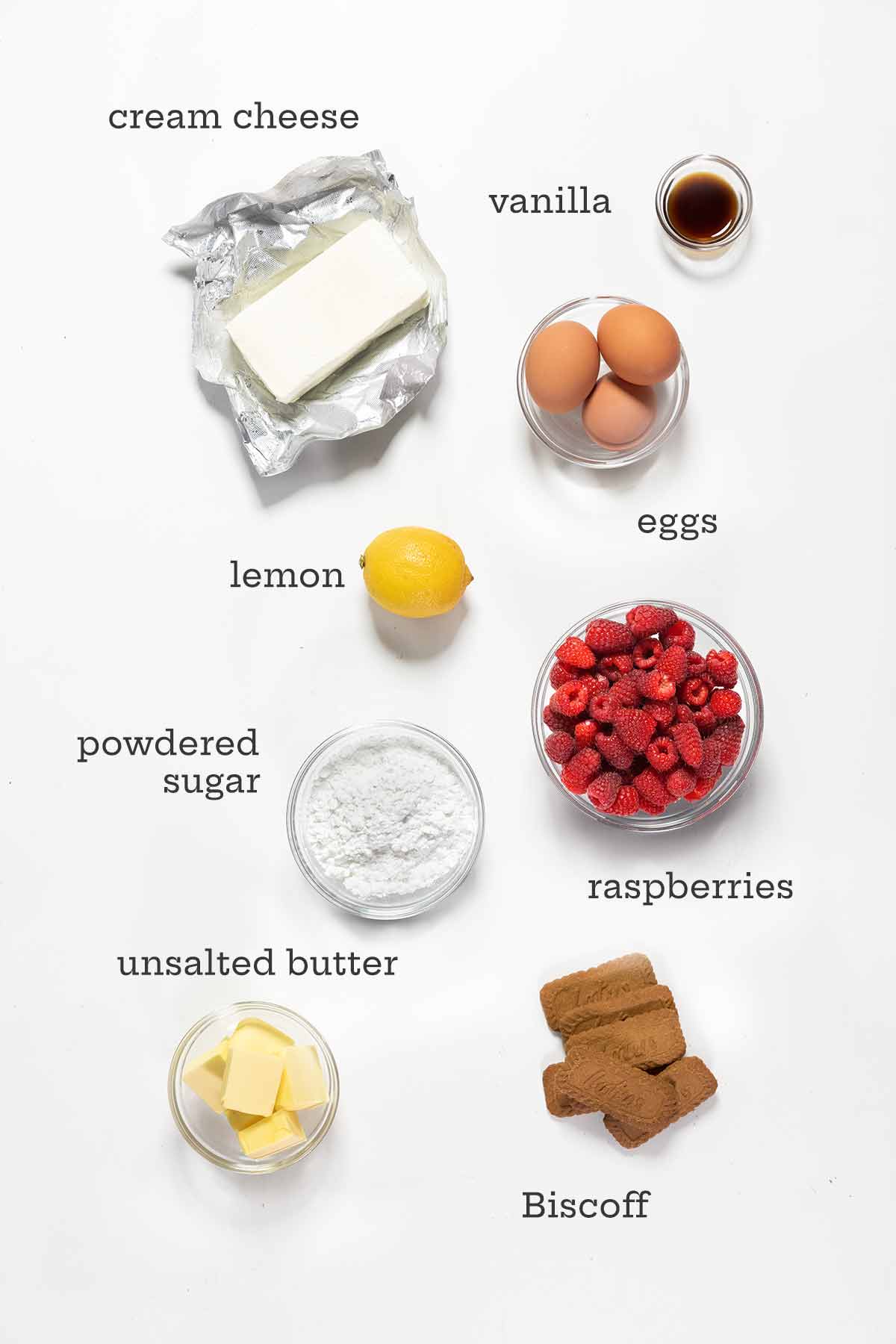 Ingredients for lemon raspberry cheesecake -- cream cheese, raspberries, lemon, eggs, sugar, butter, vanilla, and cookies.