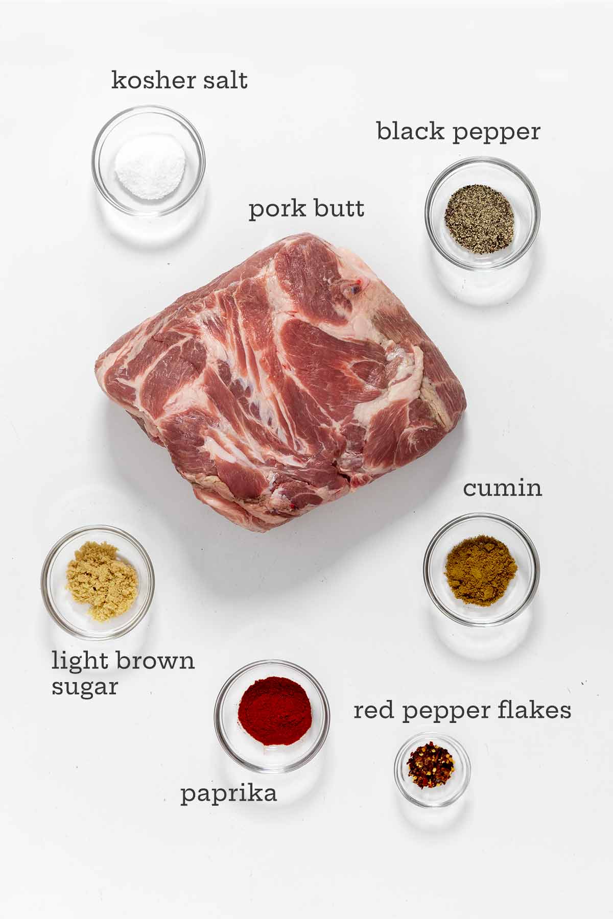Ingredients for roast pork butt --pork shoulder, salt, cumin, paprika, light brown sugar, red pepper flakes, black pepper.