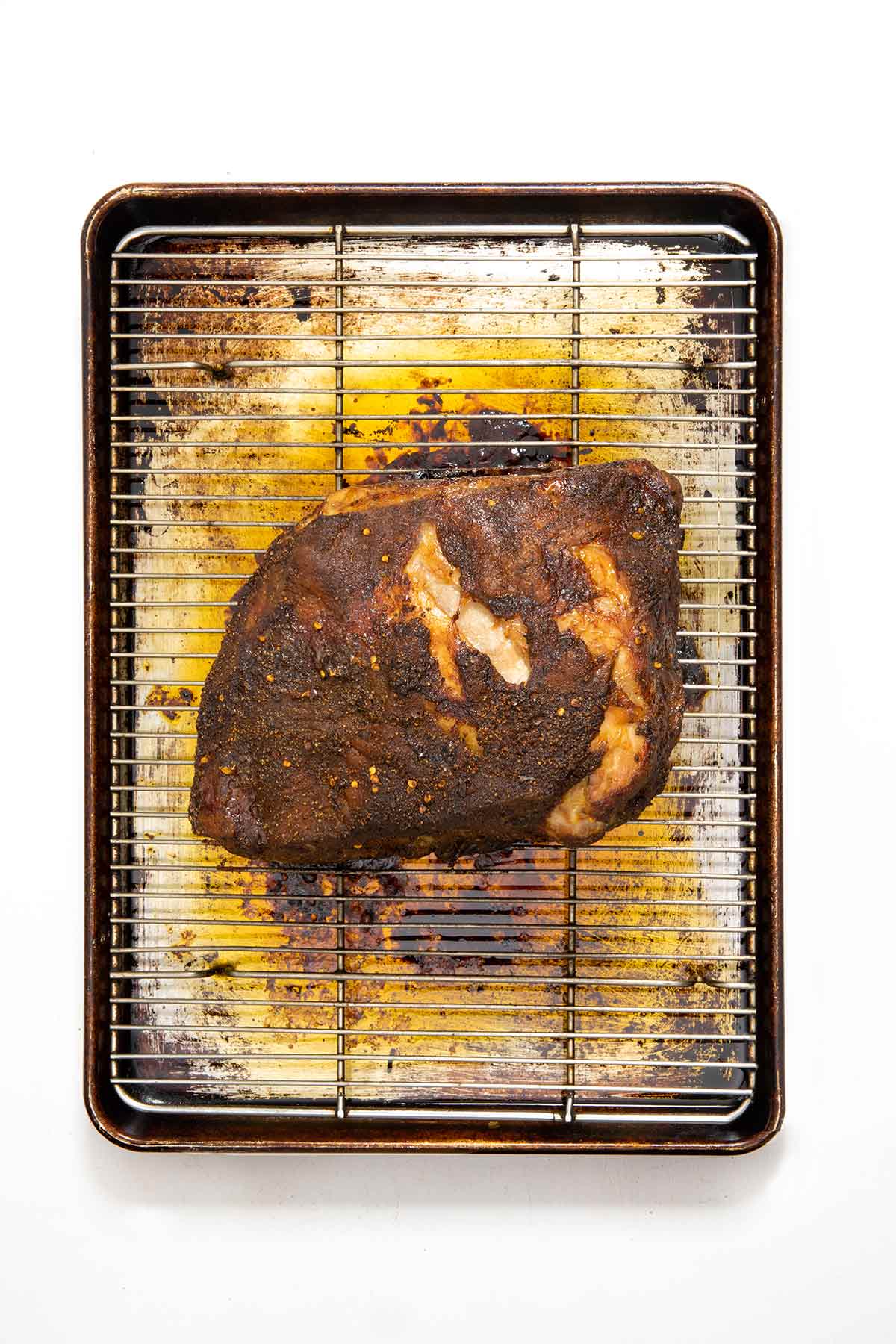 A cooked roast pork butt on a rack over a baking sheet.