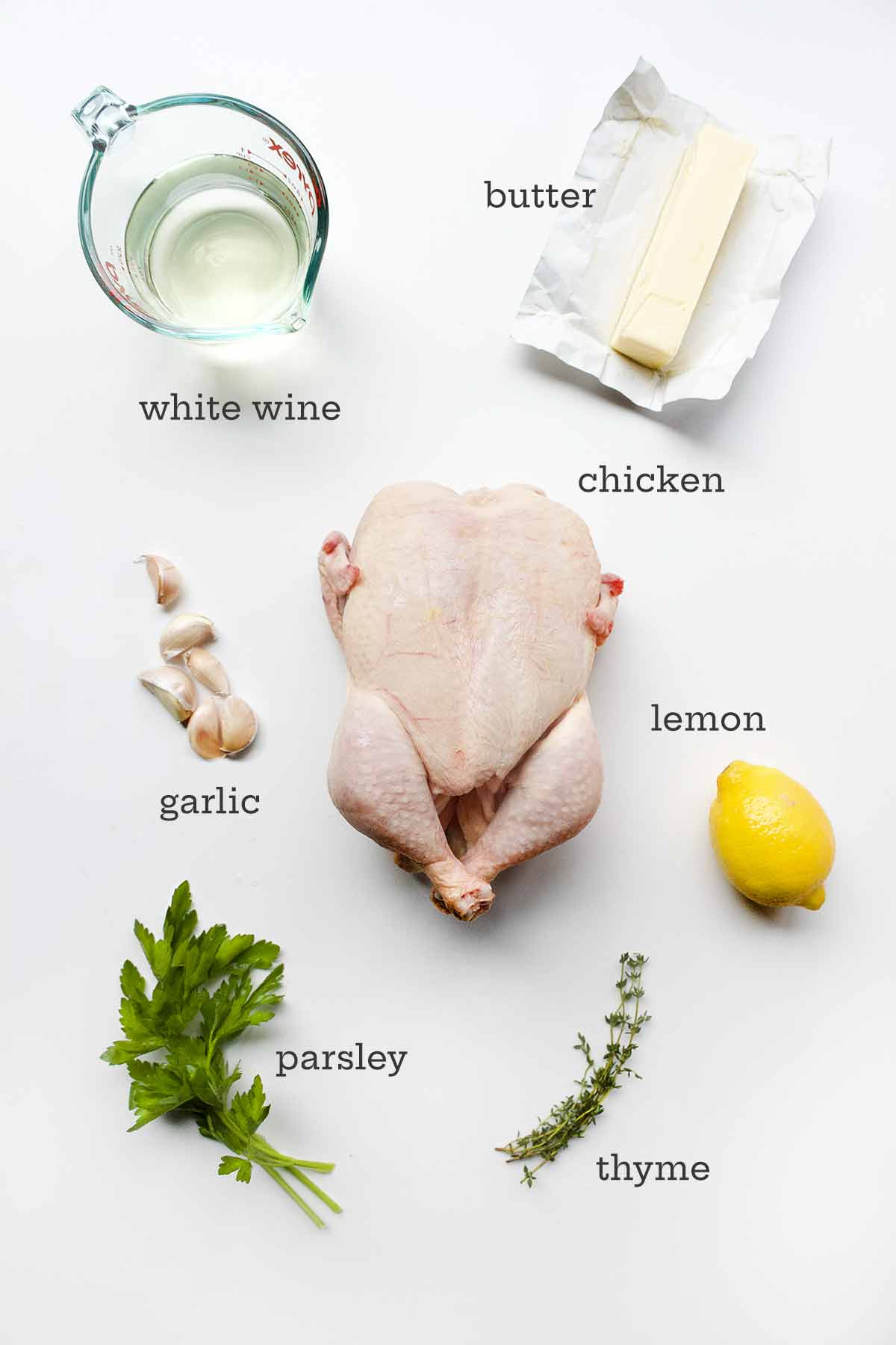 Ingredienser för spatchcockstek kyckling - kyckling, vin, smör, citron, vitlök, persilja och timjan.