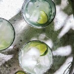 Three glasses of ultimate margarita with lime wedges.