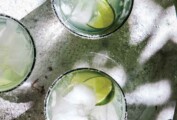 Three glasses of ultimate margarita with lime wedges.