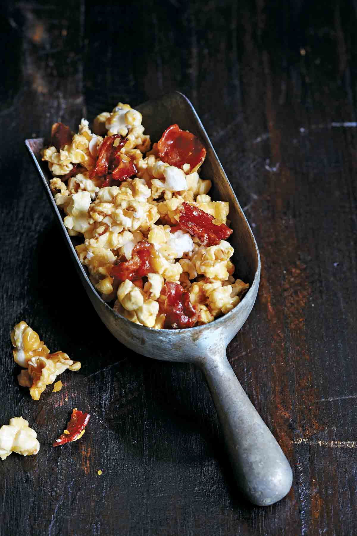 A metal scoop filled with bacon bourbon butterscotch popcorn.