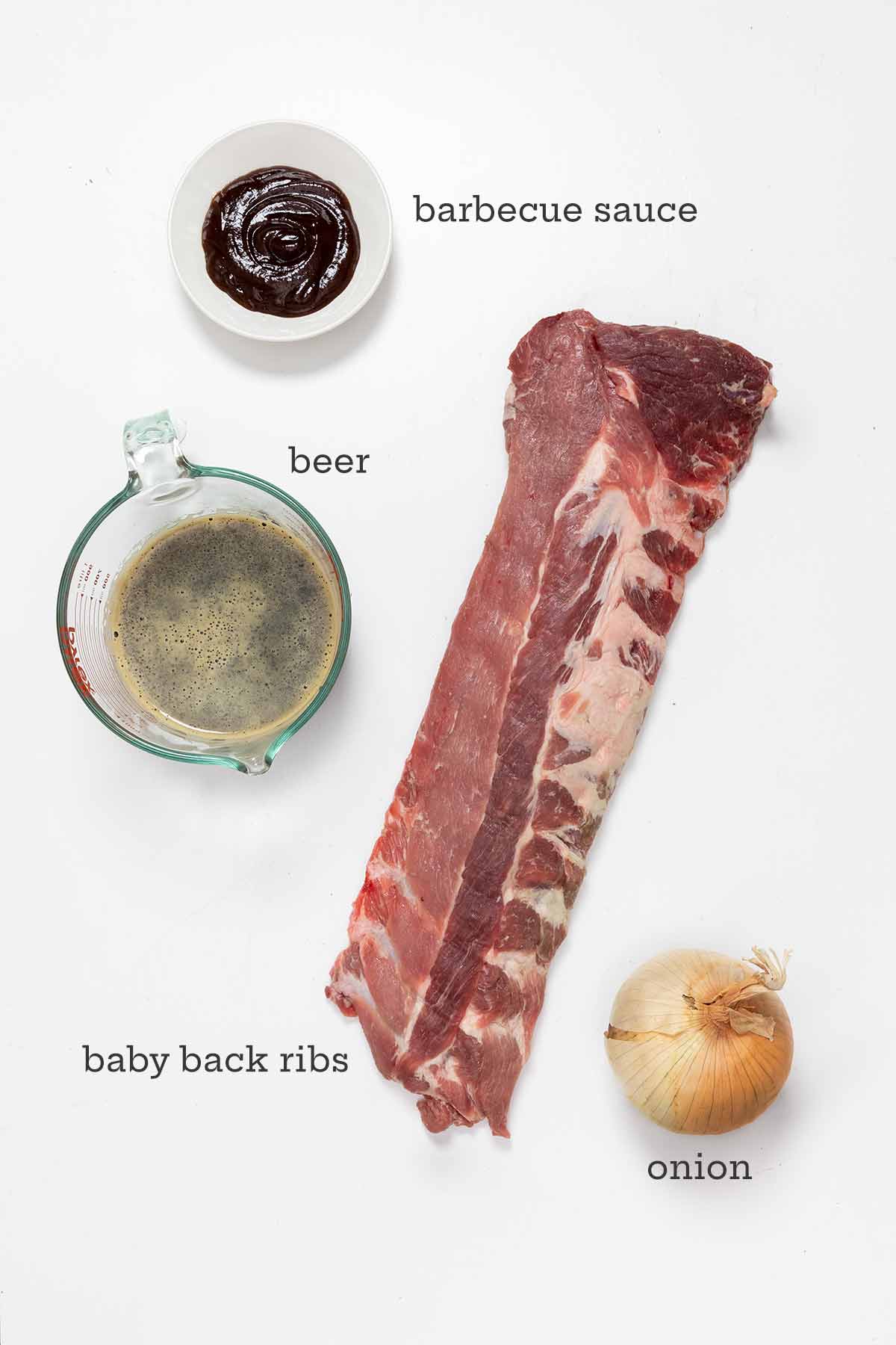Ingredients for fall-off-the-bone baby back ribs--ribs, onion, beer, and barbecue sauce