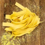 A tangle of fresh pasta noodles on a cutting board that is sprinkled with semolina.