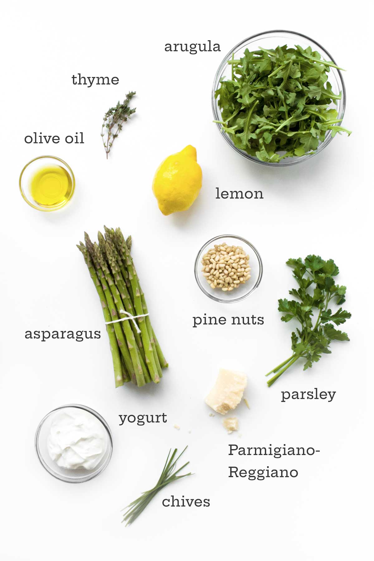 Ingredients for a raw asparagus salad: asparagus, olive oil, thyme, arugula, lemon, parsley, pine nuts, Parmesan cheese, yogurt, chives.