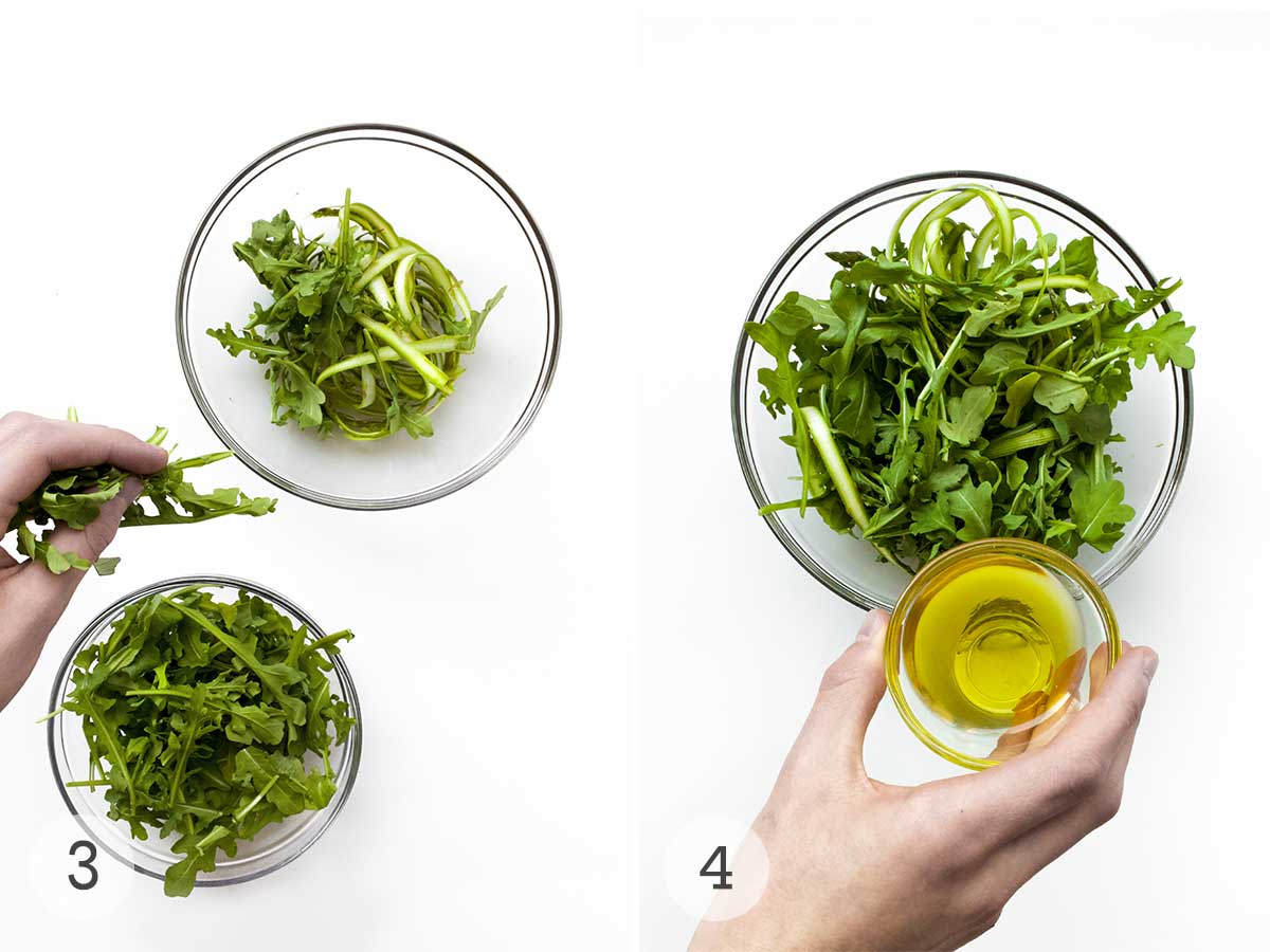 Arugula being added to a bowl of shaved asparagus and a person pouring olive oil into the bowl of salad.