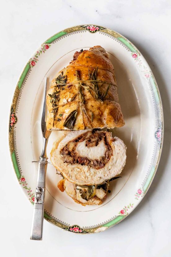 A partially sliced stuffed turkey breast on an oval platter.