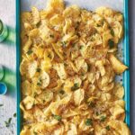 Blue tray filled with cacio e pepe potato chips--chips topped with cheese, black pepper, and parsley.