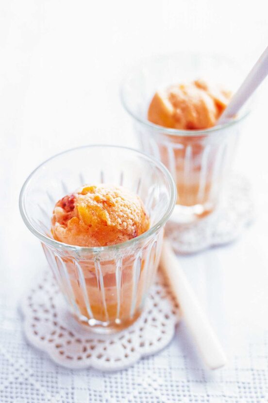 Two glass cups filled with peaches and cream ice cream.