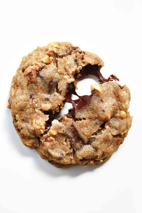 A chocolate chip cookie with nuts partially split in half.