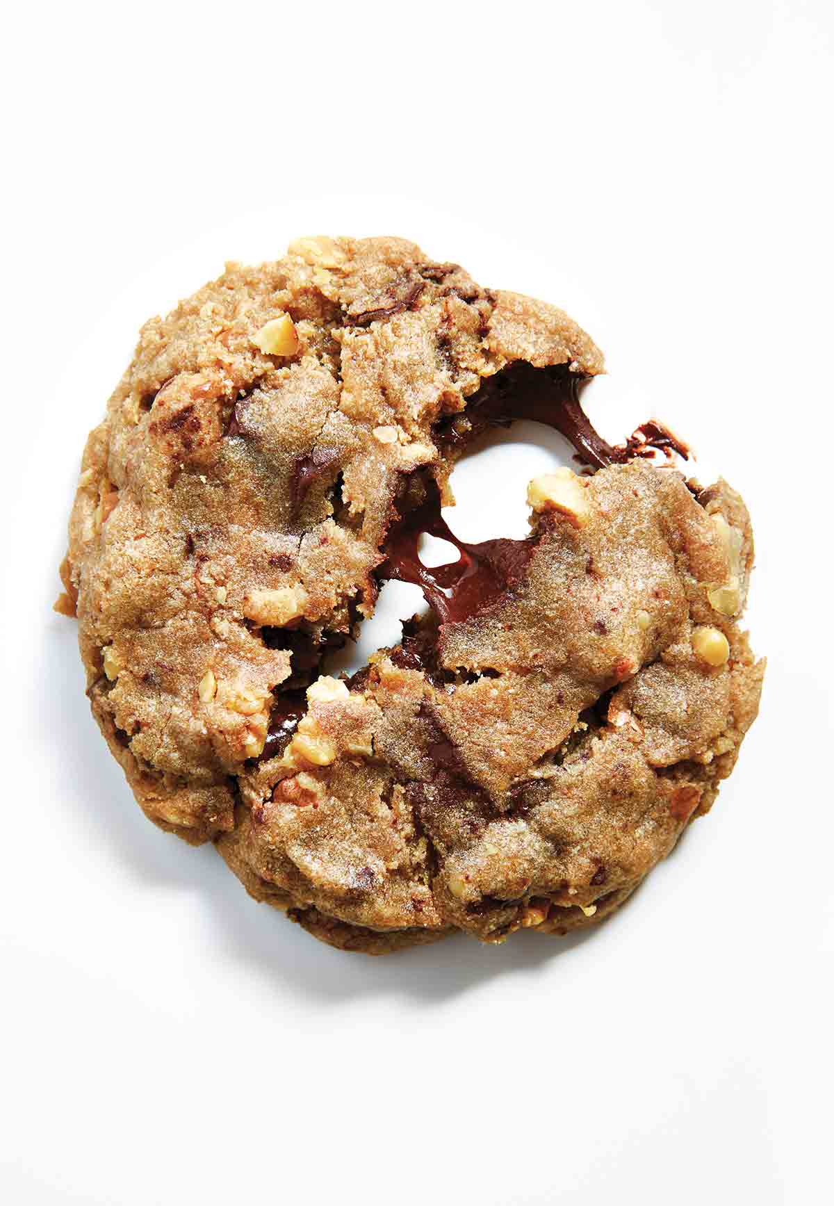 A chocolate chip cookie with nuts partially split in half.