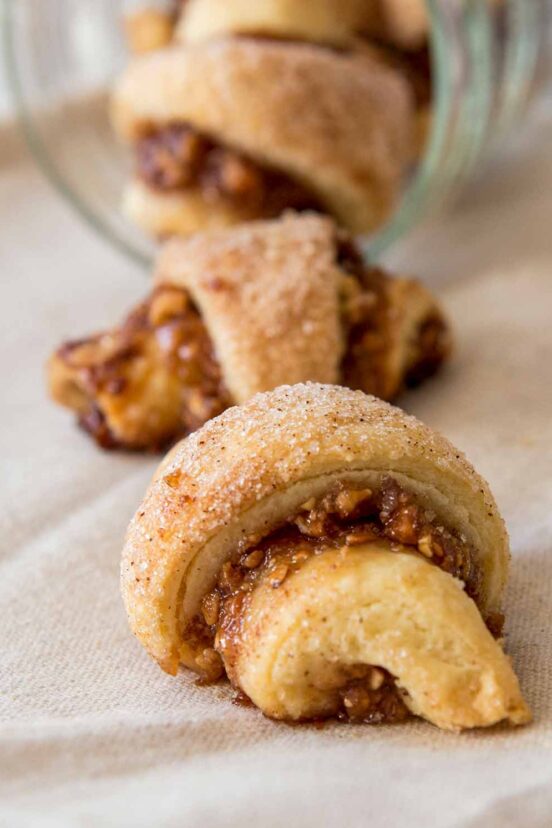 Three rugelach spilling out from a glass jar.
