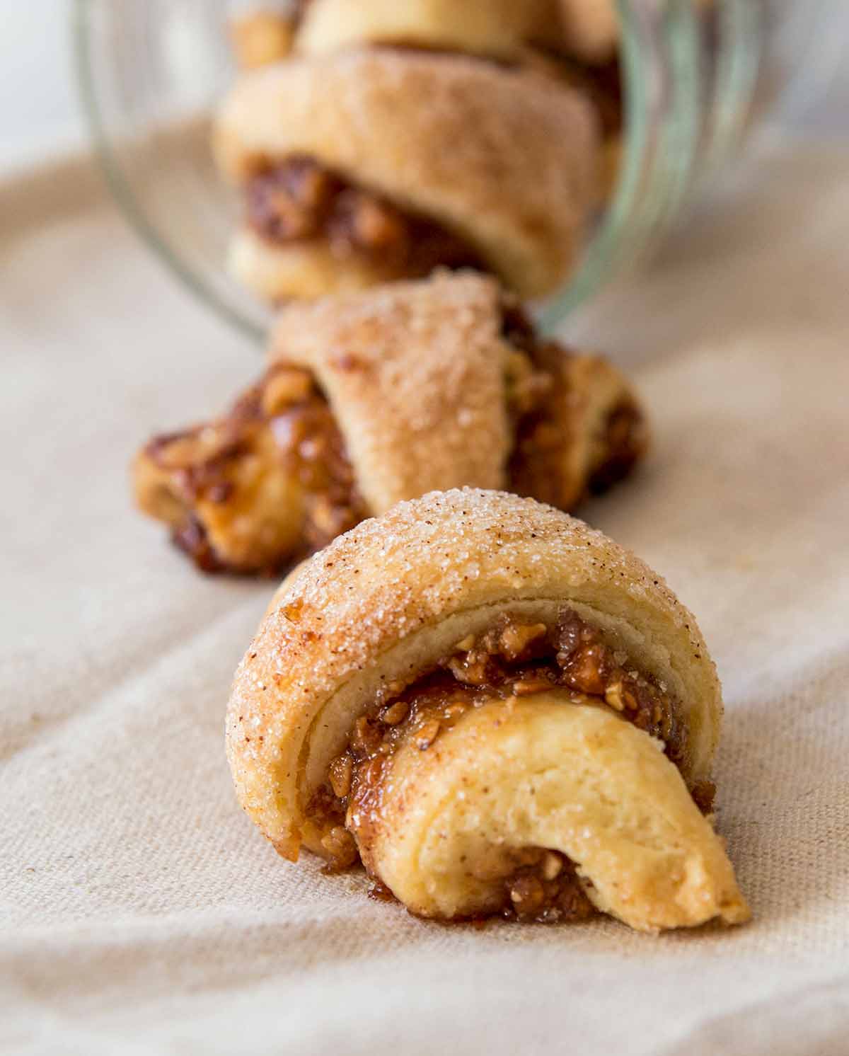 Three rugelach spilling out from a glass jar.