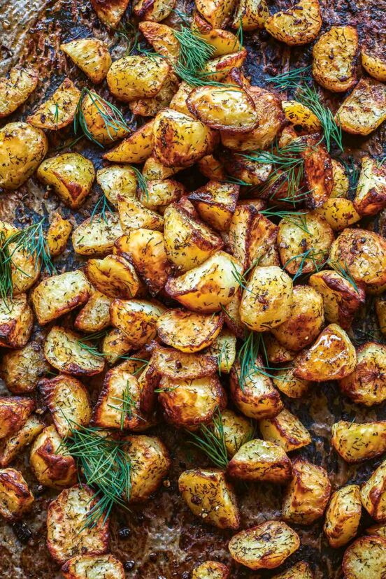 Roasted potatoes topped with dill on a baking sheet.